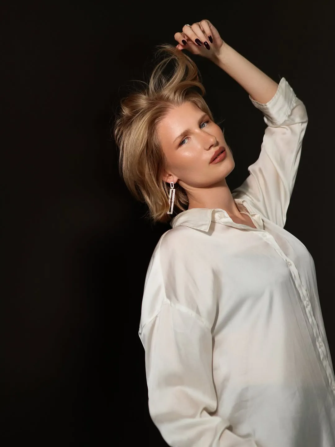 Fotosesija: modele ar tumši ķiršu nagiem uz melna fona